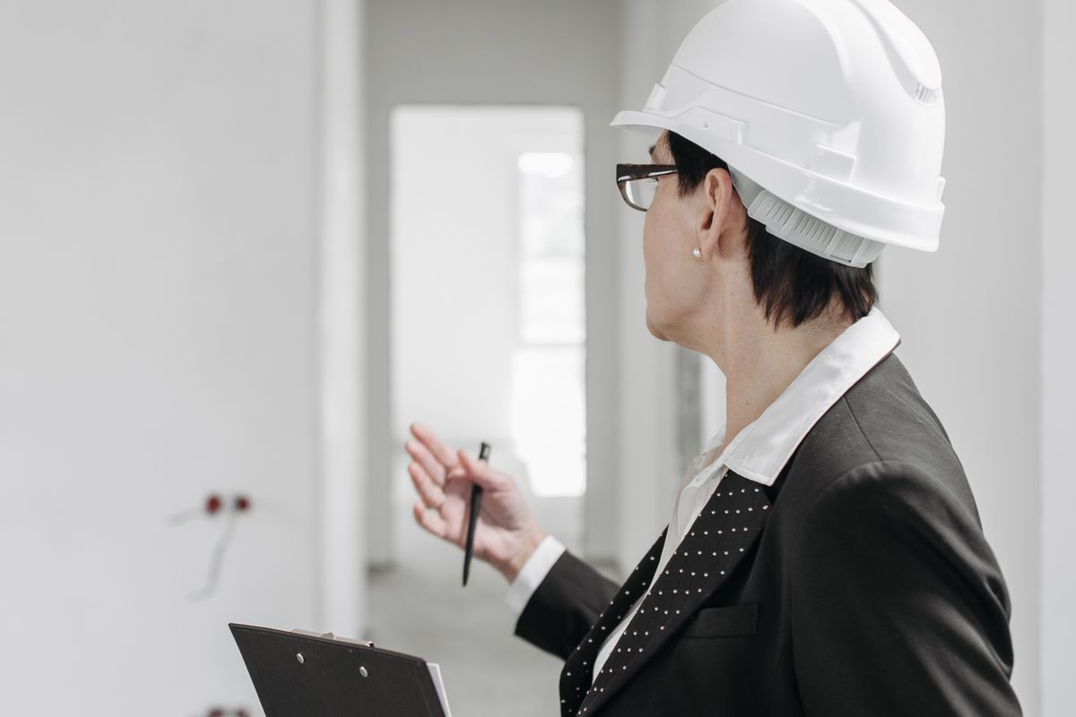 An inspector in a hard hat reviewing paperwork at a property