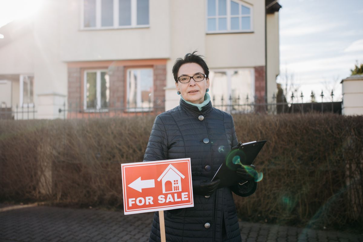 A property manager with a clipboard standing in front of a building