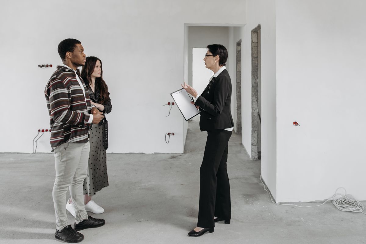 A real estate agent walking a couple through a home while sharing details on a tablet