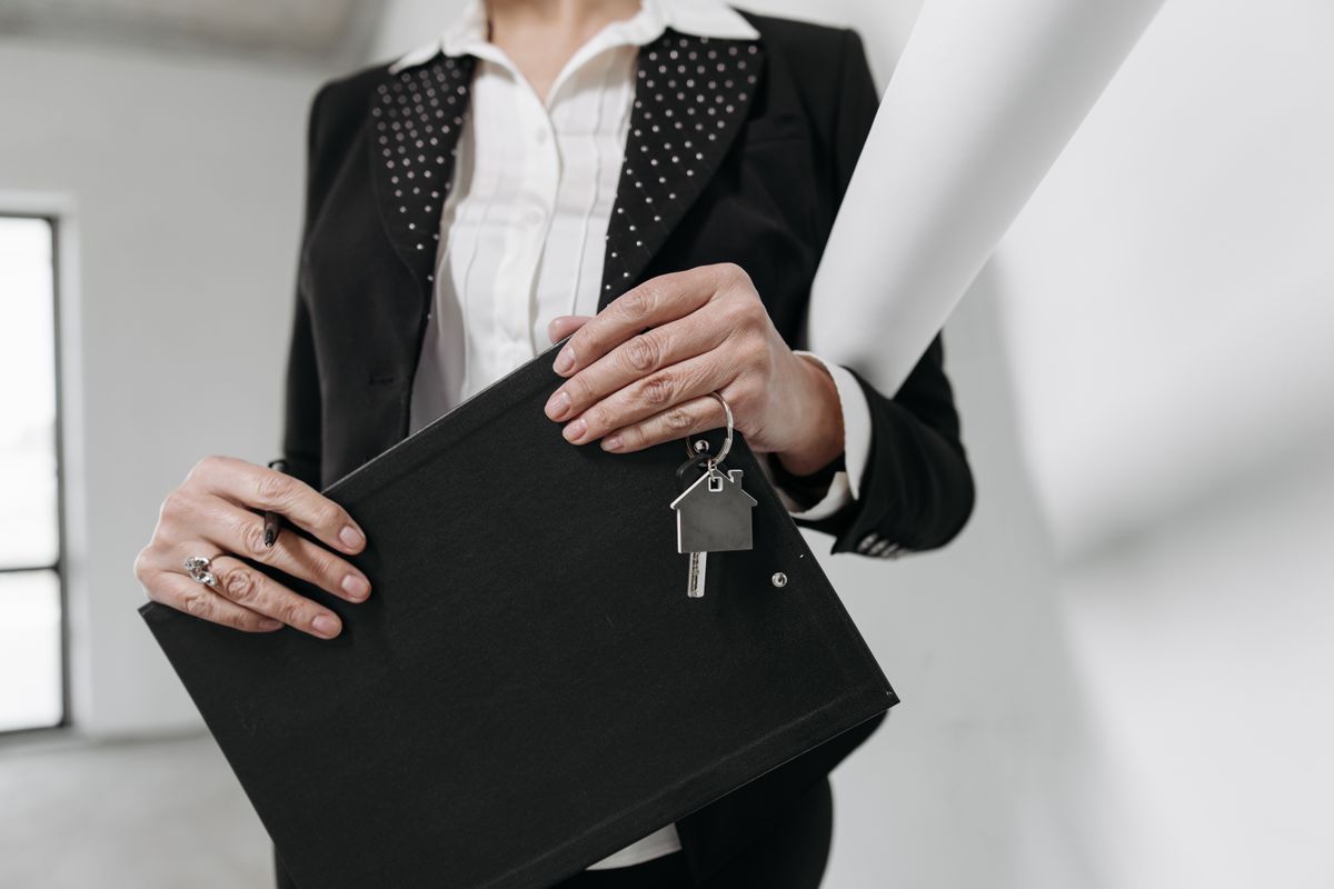 A realtor holding a clipboard and keys beside a new listing