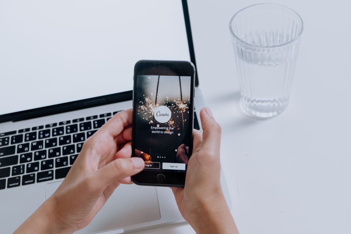 A person using a phone beside a laptop