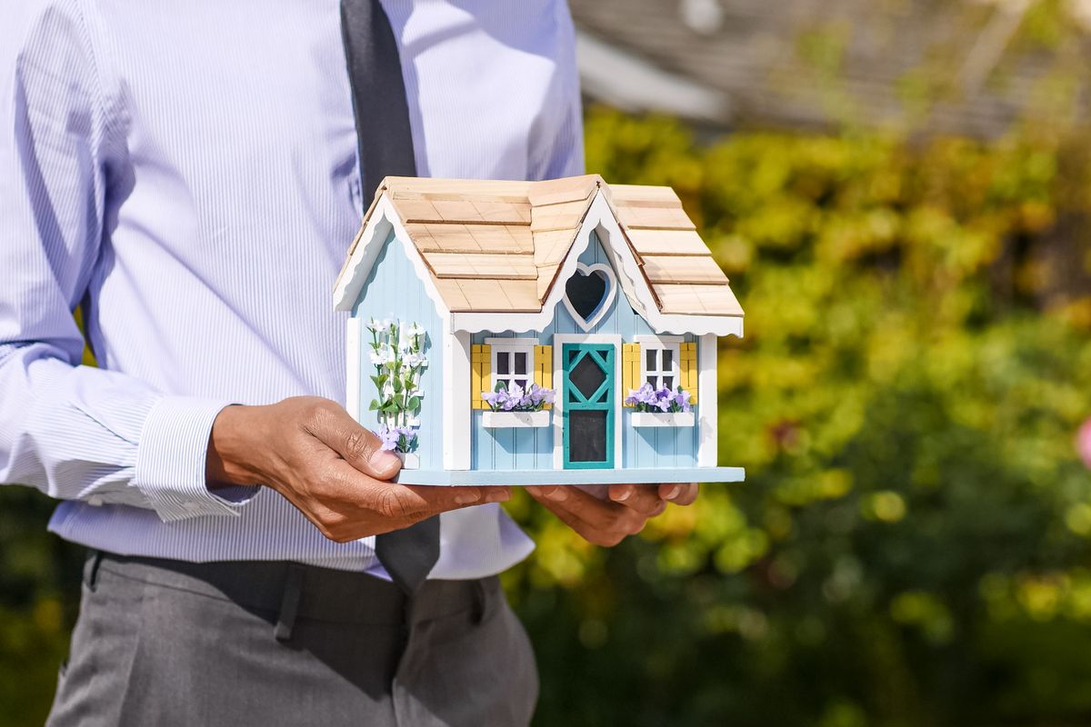 A professional holding a model house while reviewing plans